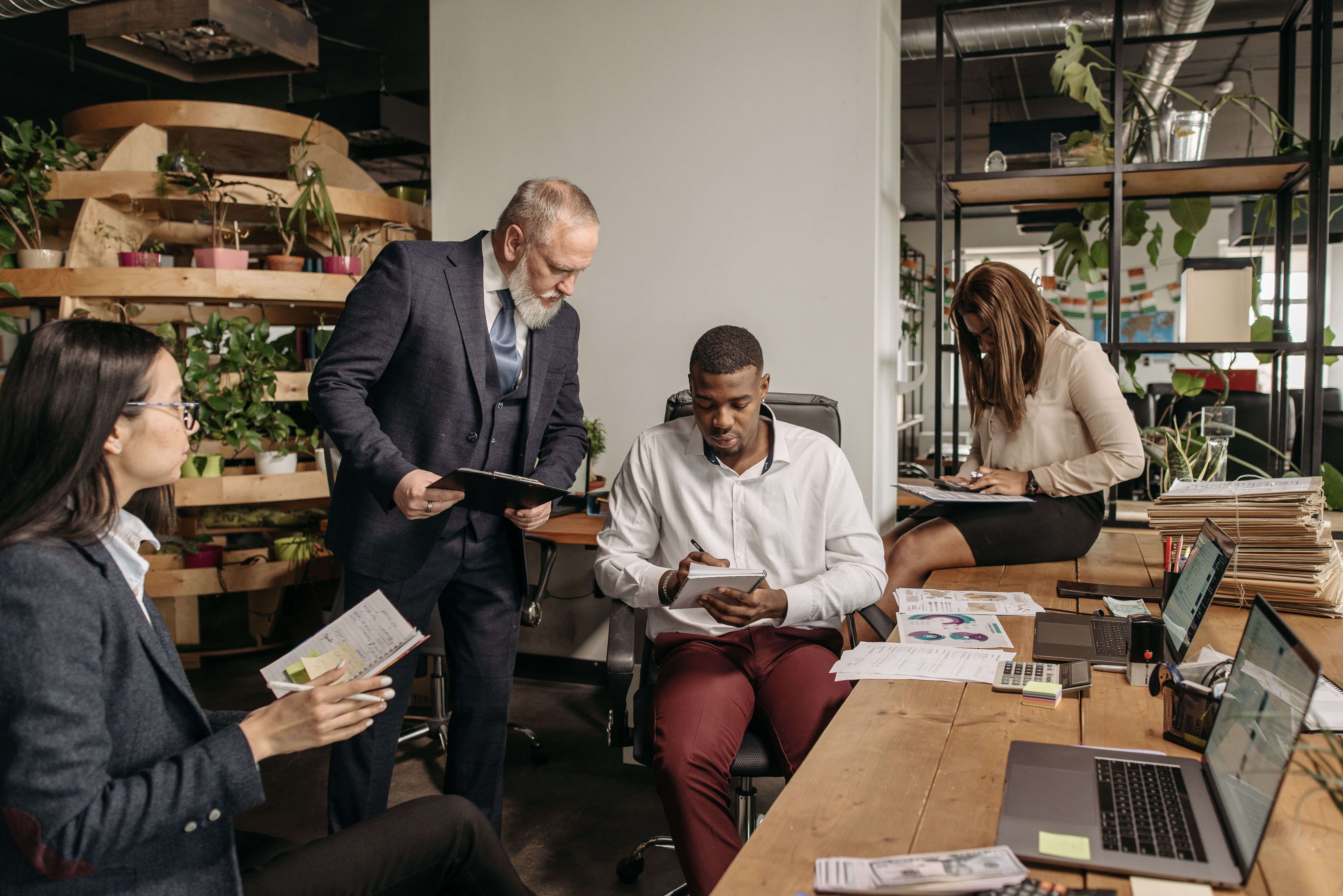 Four team members reviewing a rollout plan together around a wooden desk in the loft office